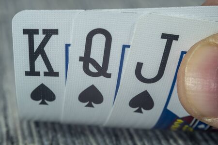Low angle closeup view of a male hand picking up and showing cards from a casino tableの写真素材