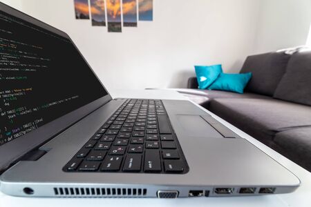 Remote home office. Low angle view of a programmer typing code on a laptop at home.の写真素材