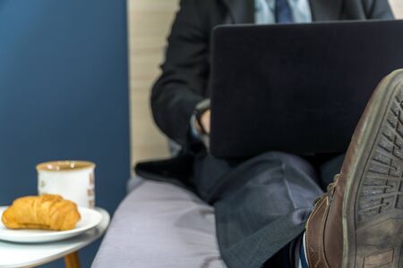 Work from home concept. Businessman dressed in a suit having a conference call on a bed with a laptop.の写真素材