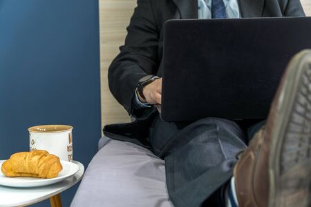Work from home concept. Businessman dressed in a suit having a conference call on a bed with a laptop.の写真素材