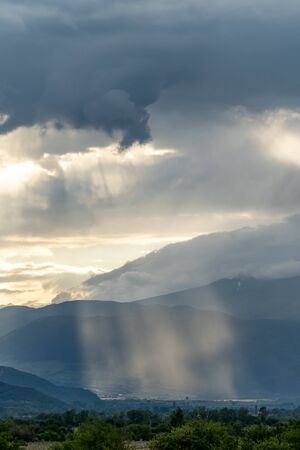 Sunbeams peaking through the clouds and lighting the Rose valley in Bulgariaの写真素材