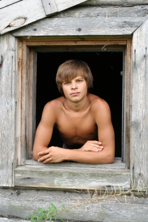 a young man sitting in the window openingの写真素材
