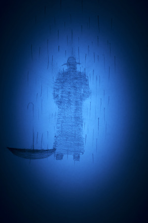 a man in a hat and coat in the rainの写真素材
