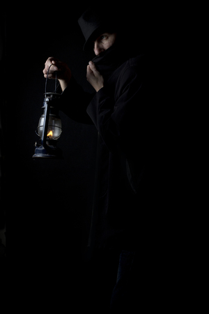 A man in the dark with a hat with a kerosene lampの写真素材