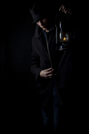 A man in the dark with a hat with a kerosene lampの写真素材