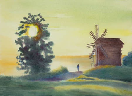 old windmill with a tree at sunsetの写真素材