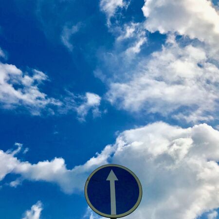 road sign up arrow on a background of blue sky with cloudsの写真素材