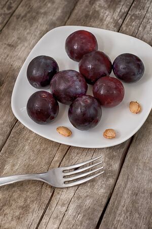 Ripe plums on a wooden backgroundの写真素材