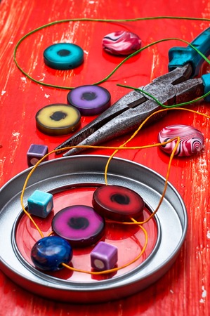beads and tools for needlework on red wooden background