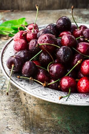 ripe large cherries in the iron bowl iron on the background in bright sunlightの写真素材
