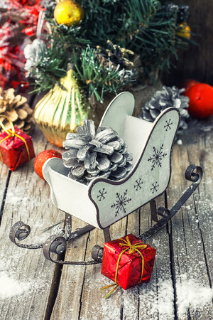 Christmas sleigh with pine cones and decorations on wooden background.の写真素材