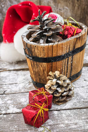 wooden tub filled with pine cones and Christmas ornaments on background of snowの写真素材