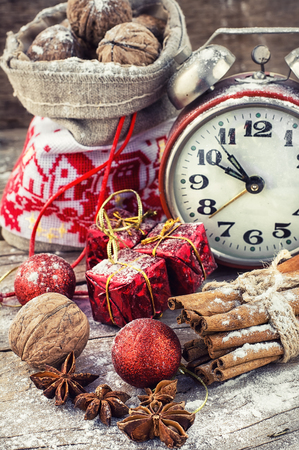 An alarm clock and bag of nuts on the background of Christmas decorationsの写真素材