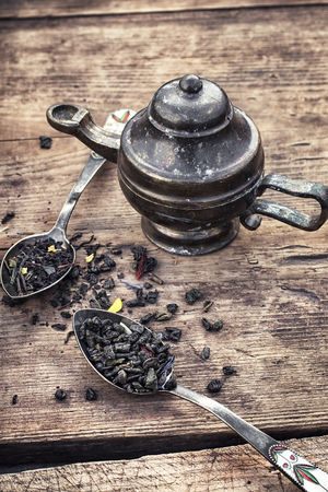Dried tea leaves in spoons on stylish background of the teapot.の写真素材