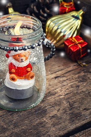 Burning Christmas candle in the shape of a bear cub in glass stylish candle holderの写真素材