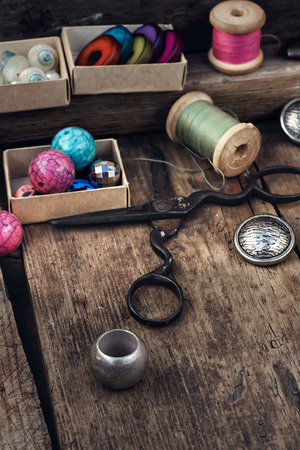 Old scissors,spools of thread,buttons and beads on wooden tableの写真素材