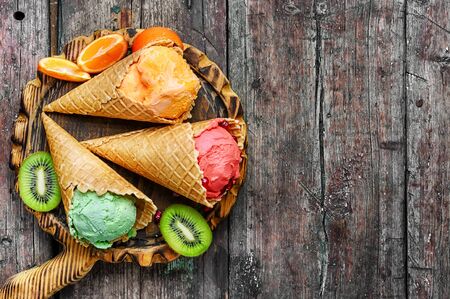 ice-cream cone with kiwi fruit and tangerines on wooden background