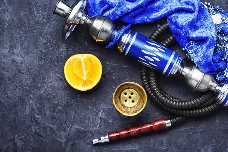Fashionable hookah with orange tobacco flavor on stone dark background.の写真素材