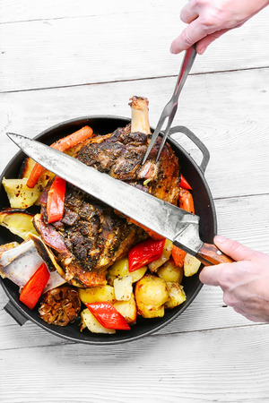 hand with the knife cutting up lamb shoulder in the pan.の写真素材