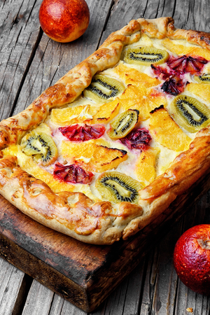 Cut piece of cheese cake with red oranges and kiwi.の写真素材