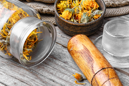 Glass pharmacy jar with dried summer flowers of calendula for therapy.の写真素材