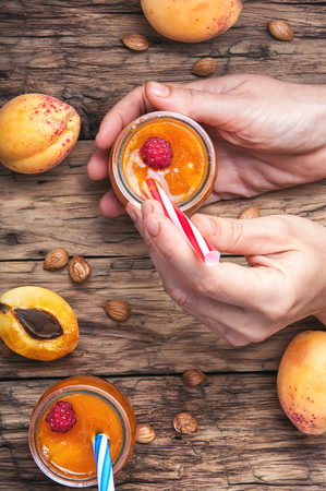 hand with jar of apricot smoothies on table in rustic styleの写真素材