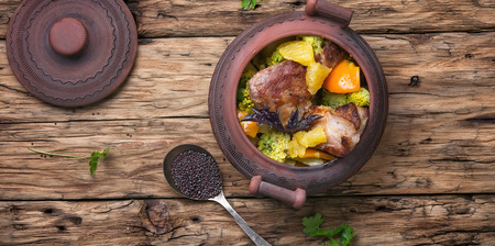 baked meat with orange sauce in a rustic potの写真素材
