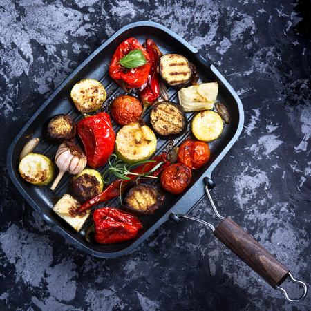 Grilled vegetables in a frying pan on blue concrete backgroundの写真素材