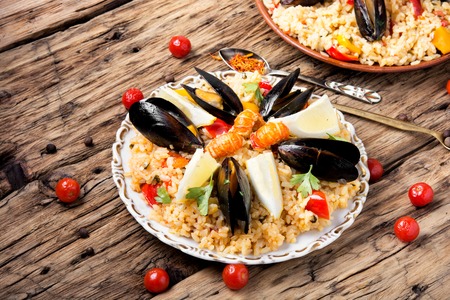 Traditional vegetable paella with seafood on wooden backgroundの写真素材