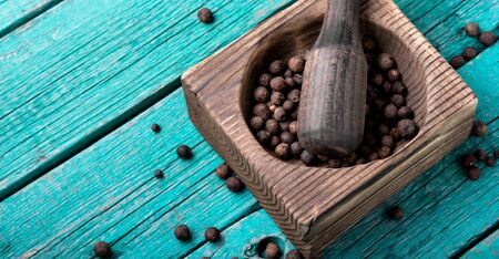 Black fragrant pepper peas in a stylish wooden mortarの写真素材