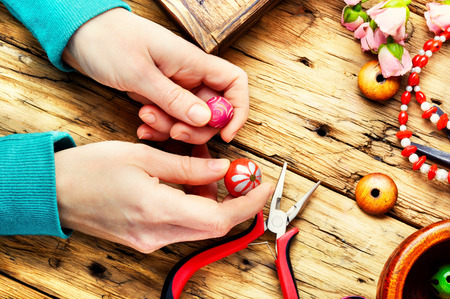 Woman makes an ornament from beads. Set of color beads. Needlework conceptの写真素材