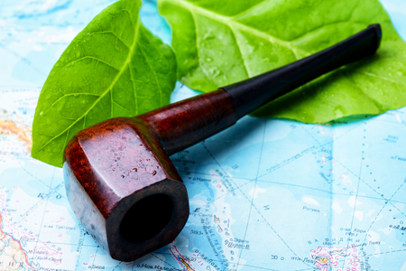 Smoking pipe, tobacco leaves on the world mapの写真素材