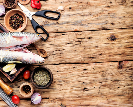 Fresh raw sea fish and ingredients for cooking on wooden backgroundの写真素材