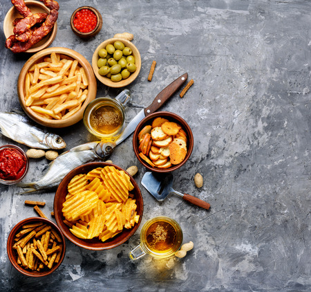 Selection of beer and snacks.Chips, fish, beer sausages on the tableの写真素材