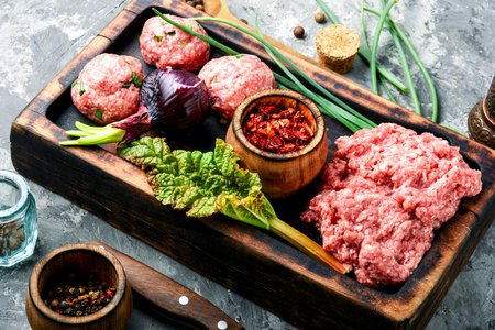 Fresh raw minced beef on cutting board and ingredientsの写真素材