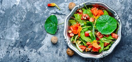 Healthy salad with flowers, nasturtium leaves, tomatoes and nuts. Summer food.の写真素材