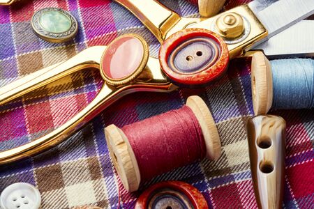Sewing tools, scissors, buttons and threads on fabric.