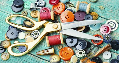 Sewing tools, scissors, buttons and threads on wooden table