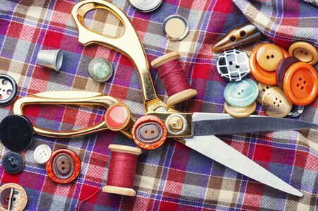 Sewing tools, scissors, buttons and threads on fabric.の写真素材