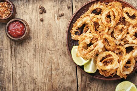 Fried squid rings breaded with lime on wooden background