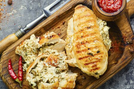 Roasted chicken breast stuffed with cheese, seasonings and sauce on the kitchen boardの写真素材