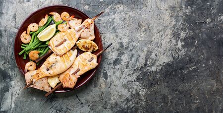 Delicious roasted squid or calamari on skewer.Barbecue squids on a plate.