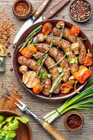 Grilled sausage with mushrooms and tomato.Fried sausages on wooden tableの写真素材