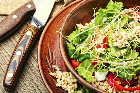Green buckwheat vegetable salad with celery stalks, micro greens and spinach on wooden tableの写真素材