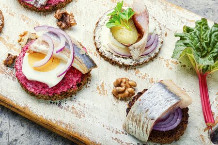 Small sandwiches or bruschettas with salted herring, beetroot and onionsの写真素材