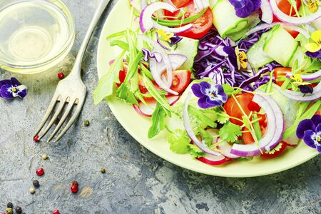 Salad with greens, tomatoes, cabbage, onions and edible flowersの写真素材