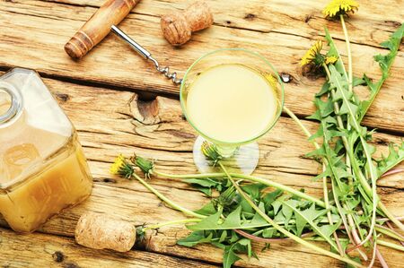 Homemade spring wine from dandelion flowers on old wooden tableの写真素材