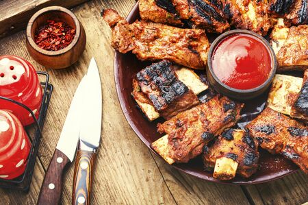Fried beef ribs with tomato sauce on a old wooden tableの写真素材