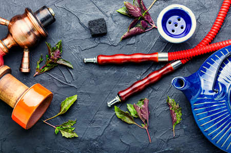 Oriental smoking hookah with tobacco on herbs Shisha with aroma of basil.