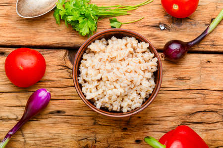 Vegetarian crumbly pearl barley porridge.Pearl barley porridge on wooden backgroundの写真素材